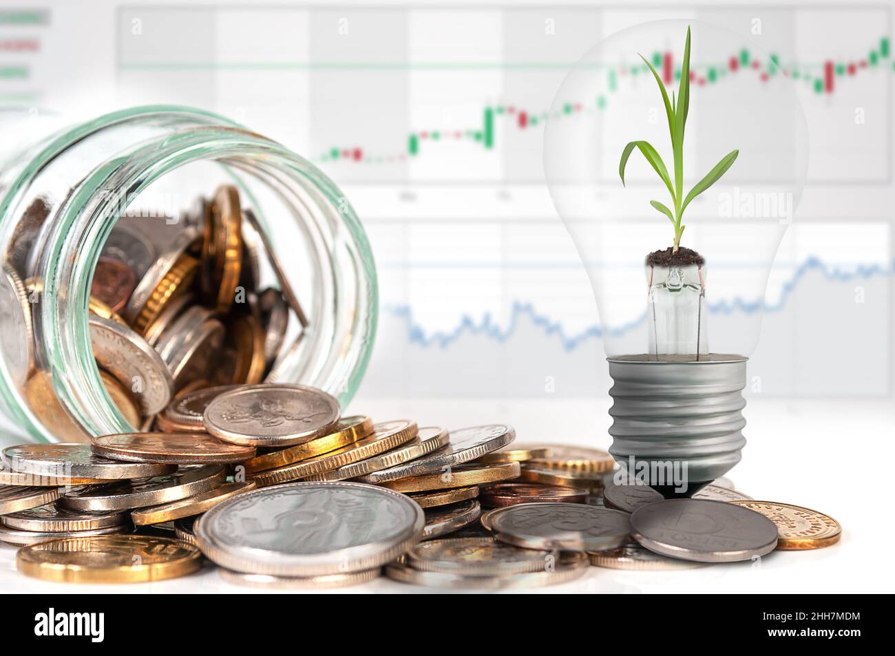Vaso in vetro con monete e lampada con germoglio verde su sfondo grafico financico. Concetto bancario sicuro e redditizio, finanze domestiche. Foto Stock