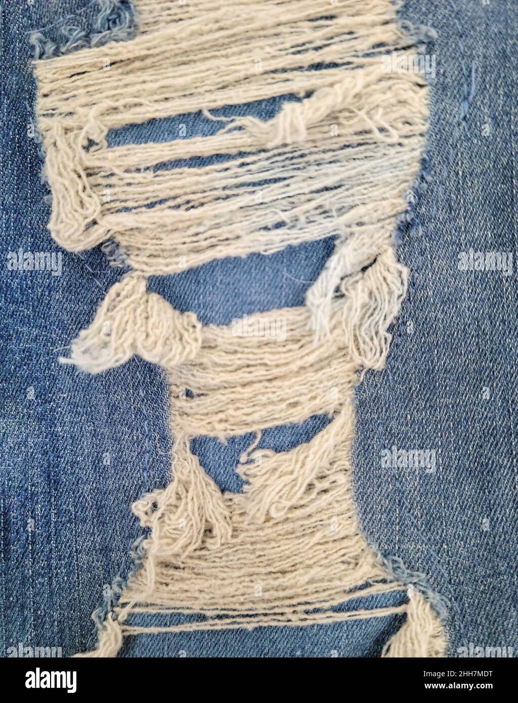 Primo piano di tessuto in denim blu con fili sfilacciati Foto Stock