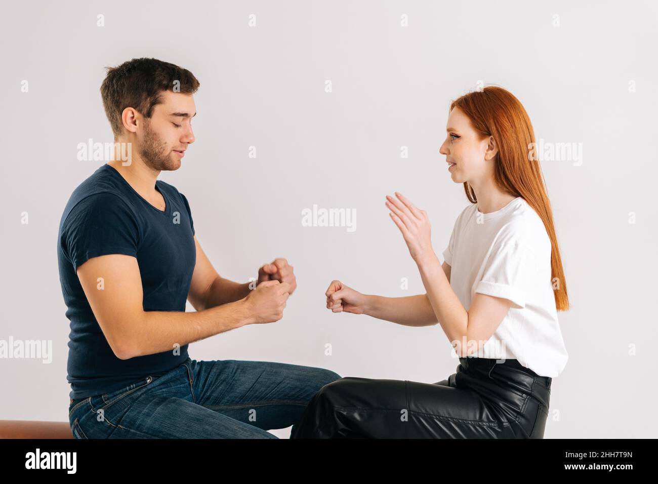 Studio girato di felice uomo e donna giovane giocando rock forbici gioco di carta su sfondo bianco isolato. Foto Stock