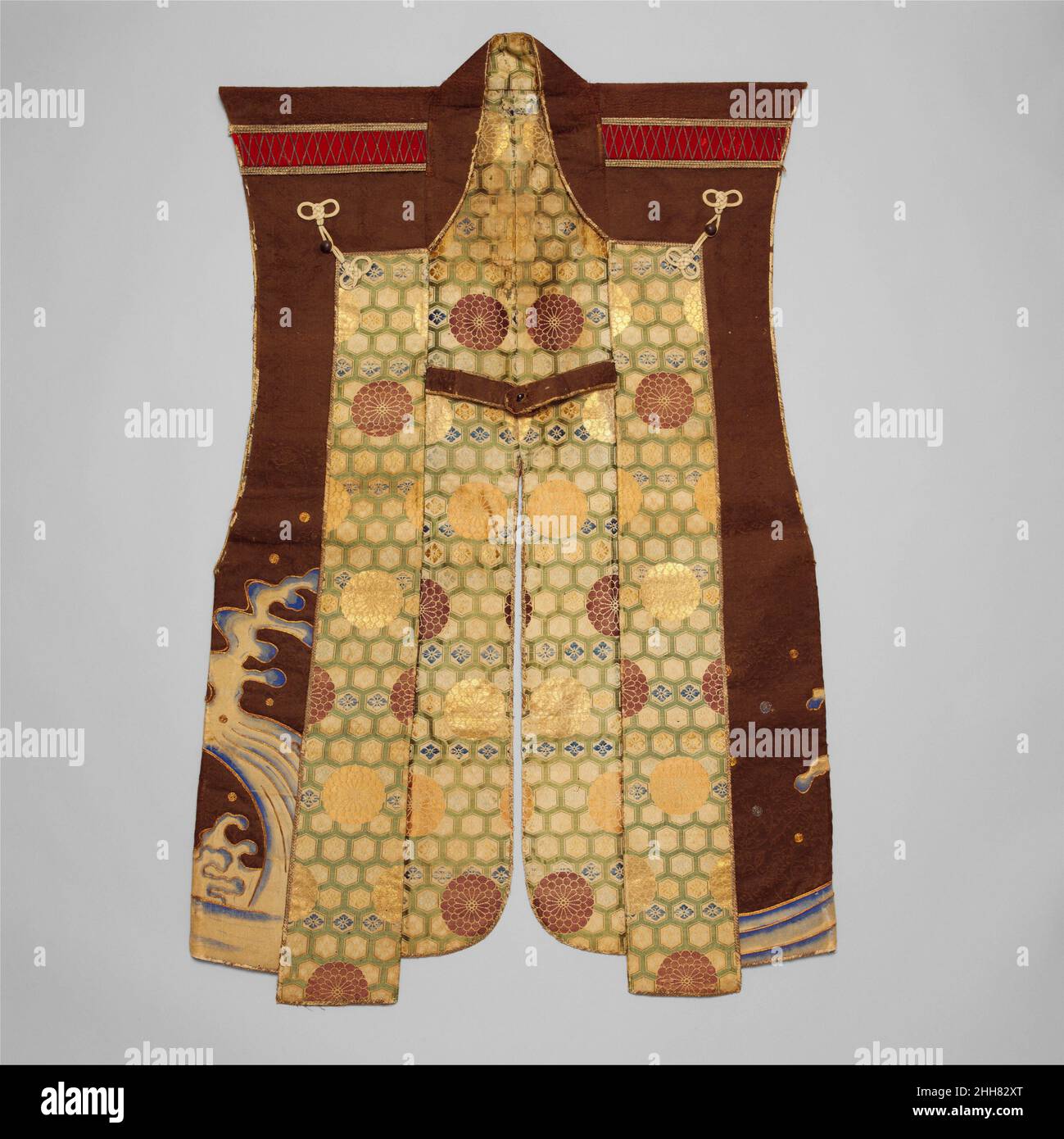 Surcoat (Jimbaori) 17th secolo giapponese Un samurai di alto rango avrebbe portato un jimbaori come questo sopra la sua armatura per la protezione contro gli elementi e come una dimostrazione del suo status e il suo mon (cresta di famiglia). Il mon sul retro di questo esempio, tre foglie di quercia all'interno di un cerchio, appartiene alla famiglia Makino, che erano daimyo (signori feudali) di Tanabe (l'odierna Prefettura di Kyoto). L'elaborata fodera, l'alta qualità dei materiali e la lavorazione fine contraddistinguono questo esempio come uno dei più fini del suo periodo. Cappotto (Jinbaori) 32638 Foto Stock