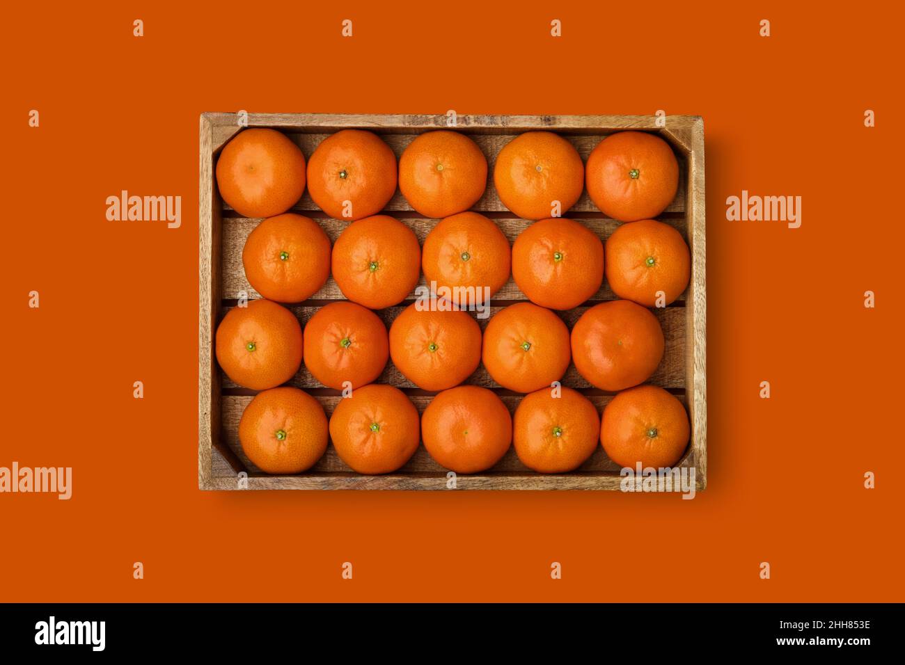 Cassa di legno di tangerini maturi su sfondo arancione. Mandarini Clementine in scatola di legno. Vista dall'alto. Adatto per la creazione di ripetizioni senza giunture. Foto Stock