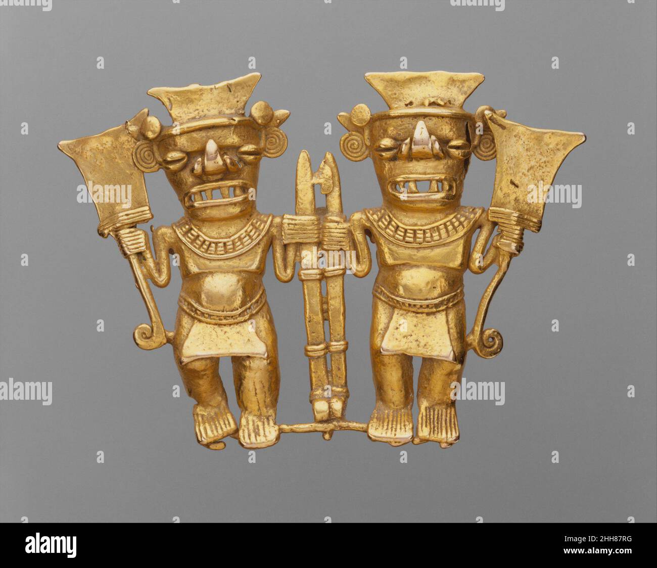 Doppio Bat-Head Figure Ciondolo 11th–16th secolo Chiriqui le figure gemelle di questo pendente dorato indossano siepi identici, lostuchi e collane a colletto largo. Ognuno contiene un lanciagranate e un club a forma di pagaia. Hanno occhi di caffè-fagiolo, bocche ampie con fangs astlike affilati, e nasi che sono rovesciati in una forma a foglia simile ai nasi dei pipistrelli dell'America Centrale. La foglia di naso è un dispositivo di rilevamento che localizza la preda del pipistrello riflettendo i suoni che emette. Gli Americani antichi devono avere venerato i pipistrelli per questa capacità apparentemente soprannaturale di vedere nella vita oscura.nella e nella morte, g Foto Stock