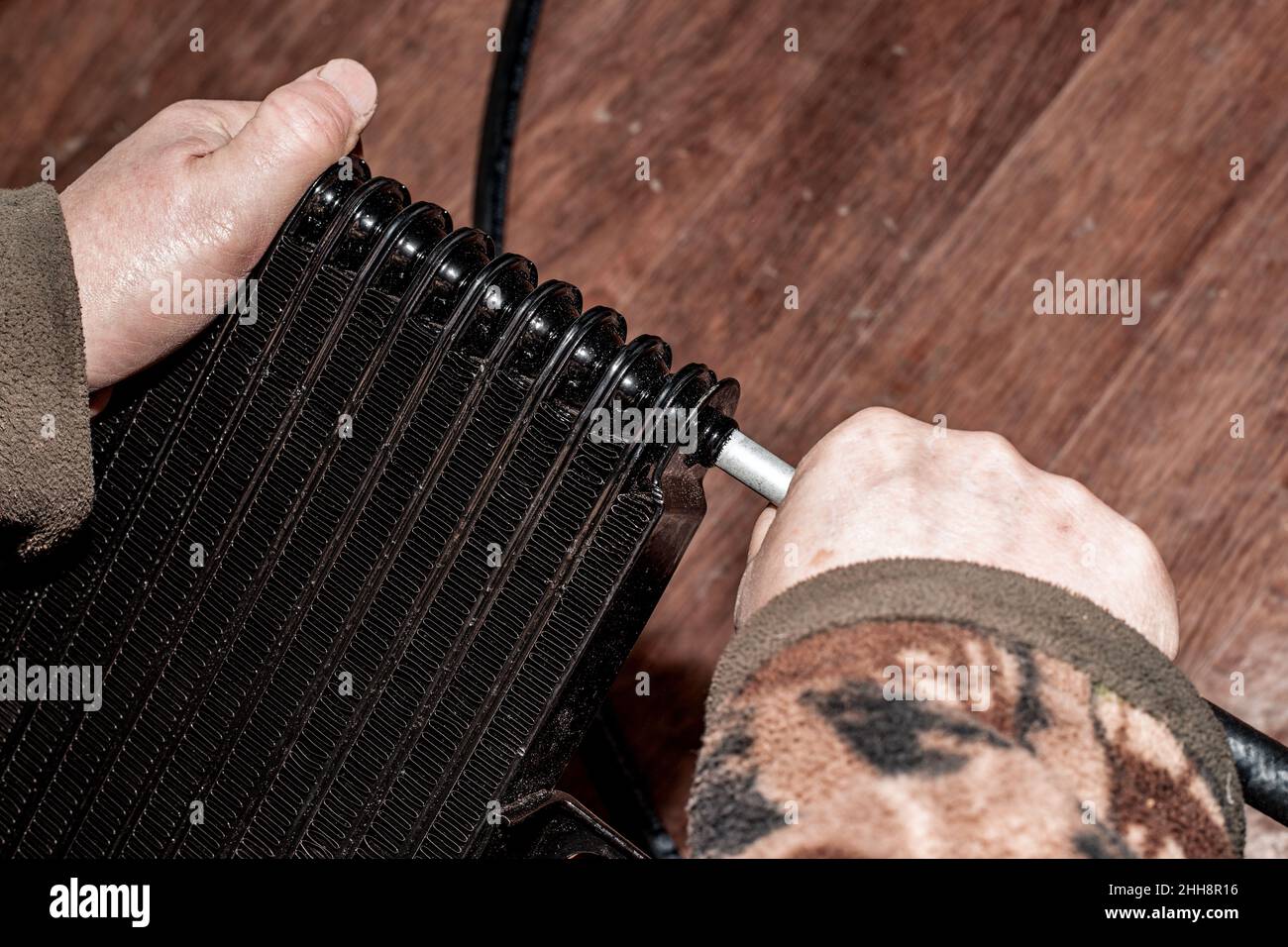 Un uomo mette un tubo flessibile in gomma resistente all'olio su un radiatore del cambio automatico. Foto Stock