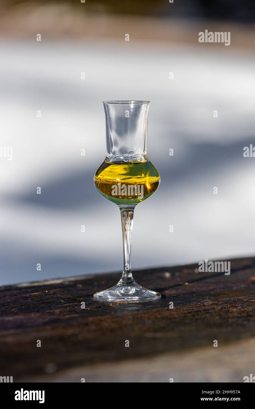 Bokeh foto di un bicchiere di Grappa aromatizzata (schnapps) a Cortina d'Ampezzo, Dolomiti, Italia Foto Stock