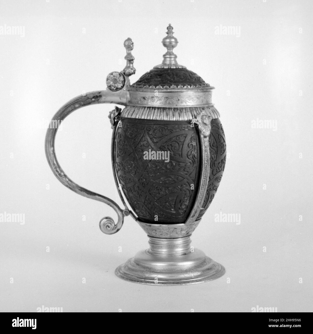 Tankard ca. 1600 il tedesco, Bamberg il cocco esotico, o "noce indiana", è stato raccolto come oggetto di poteri miracolosi nelle tesorerie di antichi templi, che può essere visto come predecessori delle tesorerie medievali della chiesa e il successivamente secolare Kunstkammer. Le origini oscure e la forma curiosa del cocco sostenevano l'idea di usarlo come antidoto. Il vino avvelenato potrebbe presumibilmente essere neutralizzato trasformando la noce direttamente in un recipiente da bere, garantendo così un contatto protettivo con il liquido alcolico contenuto all'interno. Il guscio del dado è stato lucidato per rivelare la sua bellezza e spesso orname Foto Stock