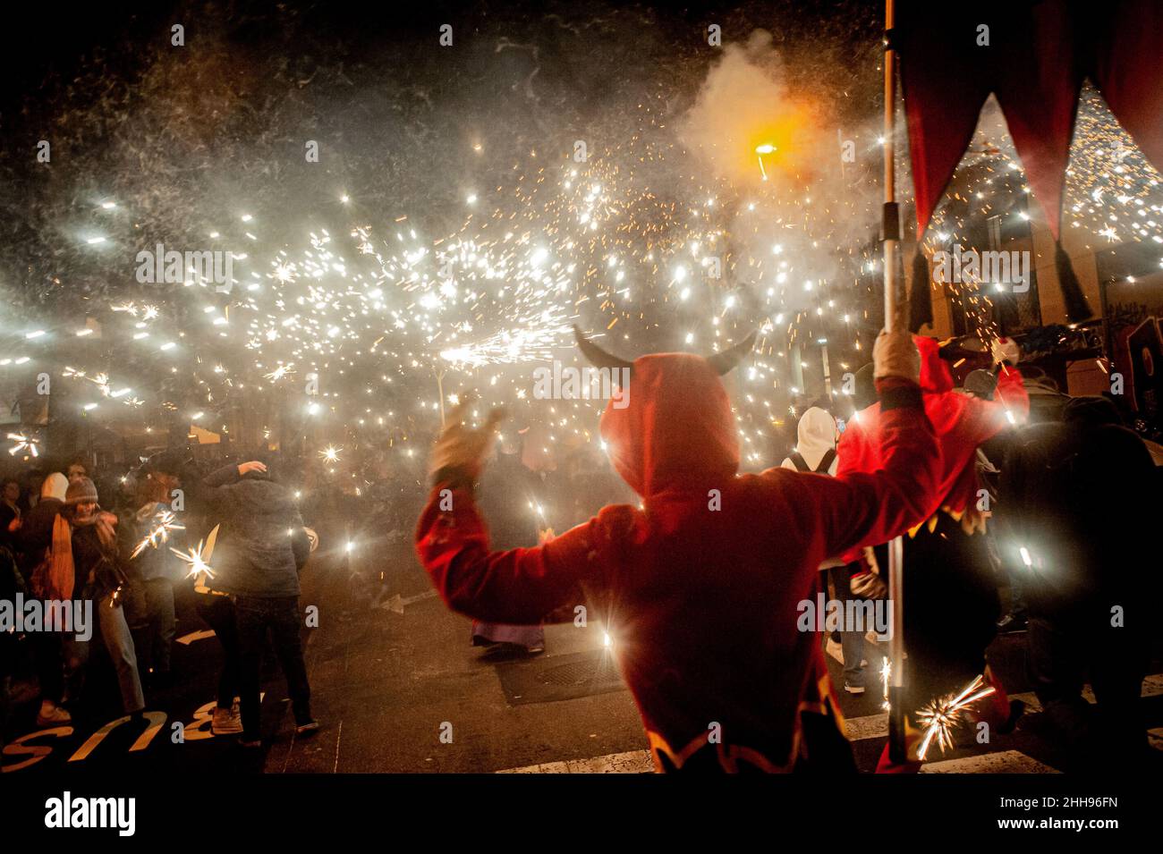 A Barcellona i diavoli fanno esplodere i pirotecnici durante un correfoc (runfire) per il festival locale del quartiere Festes de Sant Antoni. Correfocs, un'antica tradizione in cui le persone vestite da diavoli fanno saltare in aria pirati e razzi, partecipano a molti festival locali della Catalogna. Foto Stock