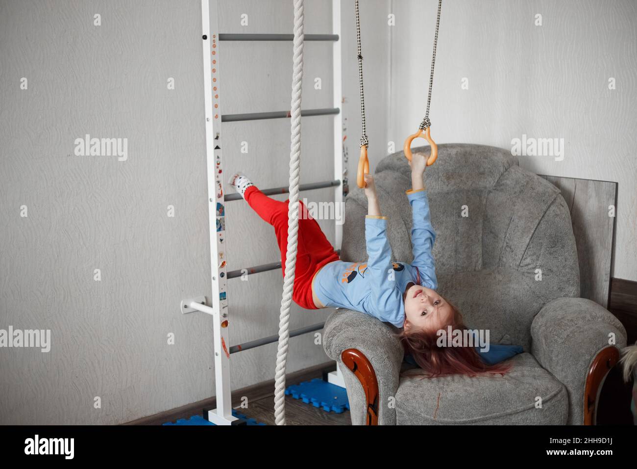 Piccola ragazza caucasica appesa alla parete sbarre esercitandosi, toned lifestyle foto in ambiente domestico Foto Stock