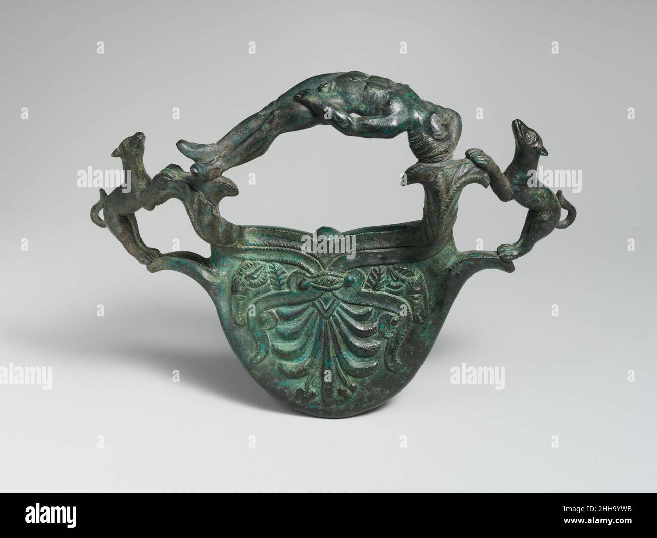 Impugnatura in bronzo con cani fiancheggianti una giovinezza reclinata 4th secolo a.C. Etrusca questa magnifica impugnatura può ben rappresentare l'Endimion addormentato, l'amato cacciatore di Artemis, al quale fu concessa immortalità ed eterna giovinezza ma anche sonno perpetuo. Il soggetto è particolarmente appropriato, poiché tali impugnature sono spesso associate a grandi vasi di bronzo che servivano come urne di cremazione. Strettamente parallelo a questa maniglia è una coppia - uno ora nel Boston Museum of fine Arts e l'altro nell'Antichenmuseum, Berlino - che proviene da Città della Pieve, a nord di Orvieto (antico Volsinii). Impugnatura in bronzo wi Foto Stock