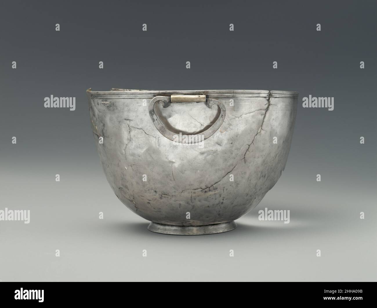Ciotola d'argento con manici oscillanti fine 4th sec. a.C. Greco, Italiano del Sud nel 1895 la tomba di un guerriero gallico fu scavata in una necropoli a Montefortino, a circa trenta miglia ad ovest di Ancona nel centro Italia. Il cimitero è quello dei Galli che nel IV secolo a.C. iniziarono ad invadere l'Italia centrale e a fare incursioni fino a sud della Puglia. La tomba conteneva armi di ferro, vasi di bronzo e terracotta, un anello d'oro e cinque vasi d'argento che doveva essere portato come bottino da un'altra parte d'Italia. La zoccoletta include una caraffa d'argento (08.258.51), una ciotola d'argento con manici oscillanti Foto Stock
