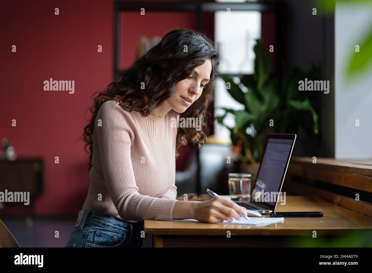 Ha messo a fuoco il revisore giovane donna che fa la documentazione sul posto di lavoro in ufficio, preparando il prospetto finanziario Foto Stock