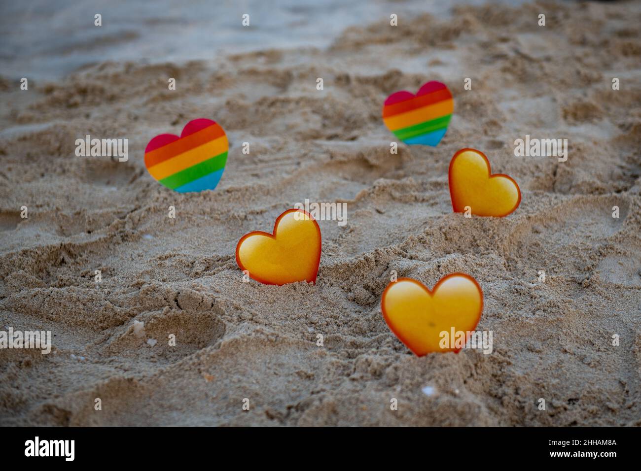 sul mare lgbt e cuori gialli nella sabbia stand Foto Stock