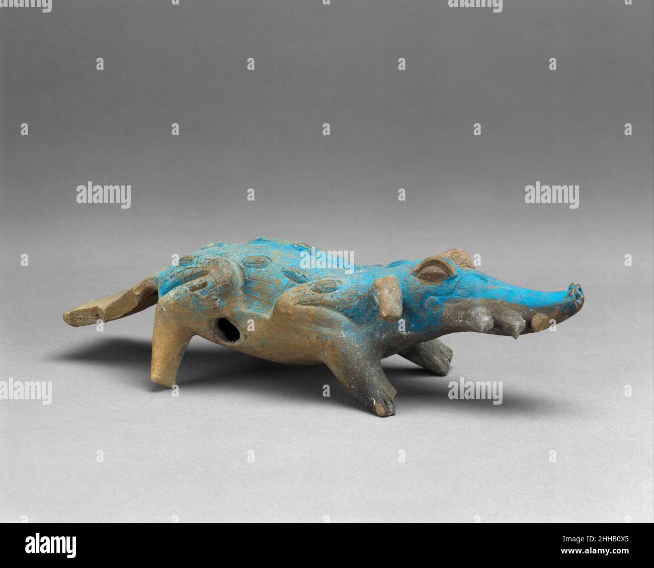 Crocodile Rattle 8th Century Maya questa figura in ceramica zoomorfa è stata modellata a mano nella forma di un coccodrillo. Funziona sia come un fischio: I fori d'aria appaiono davanti alle gambe posteriori dell'animale sul lato inferiore, e una bocchetta d'aria si trova sotto il collo, e un picchiettio, i pallini di argilla sono all'interno della metà anteriore della figura. Il coccodrillo ha palpebre rialzate che sporgono dalla sommità del suo lungo muso capovolto con narici rotonde e tre denti triangolari che sporgono orizzontalmente da ogni lato della sua bocca. Le orecchie flopped e flaring tipo cane sporgono dai lati posteriori della testa dietro gli occhi. ITS Foto Stock