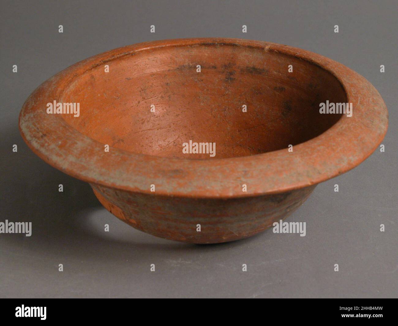 Bowl 4th–7th Century Coptic la ciotola con bordo flangiato è un'imitazione di una merce chiamata North African Red Slip, importata in tutto il mondo romano e bizantino. Questa ciotola è stata realizzata in un laboratorio locale di ceramica nelle oasi del deserto occidentale. Ha un foro nella parte inferiore, che avrebbe potuto essere fatto quando gli escavatori stavano recuperando i manufatti dal sito. Recipiente 477343 Foto Stock