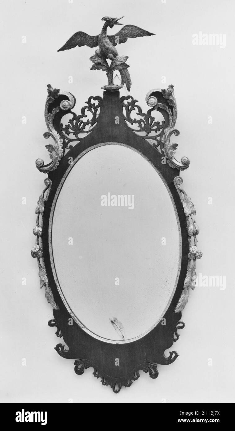 Looking Glass 1770–1800 American mentre la forma ovale di questo vetro Looking ricorda lo stile neoclassico, introdotto negli Stati Uniti dal 1790, la cornice, che presenta una finica simile a phoenix, un'apertura traforata e S-scrolls intagliati e dorati, indica la ritenzione dell'estetica rococò che era popolare prima della Rivoluzione americana. Vetro 4865 Foto Stock
