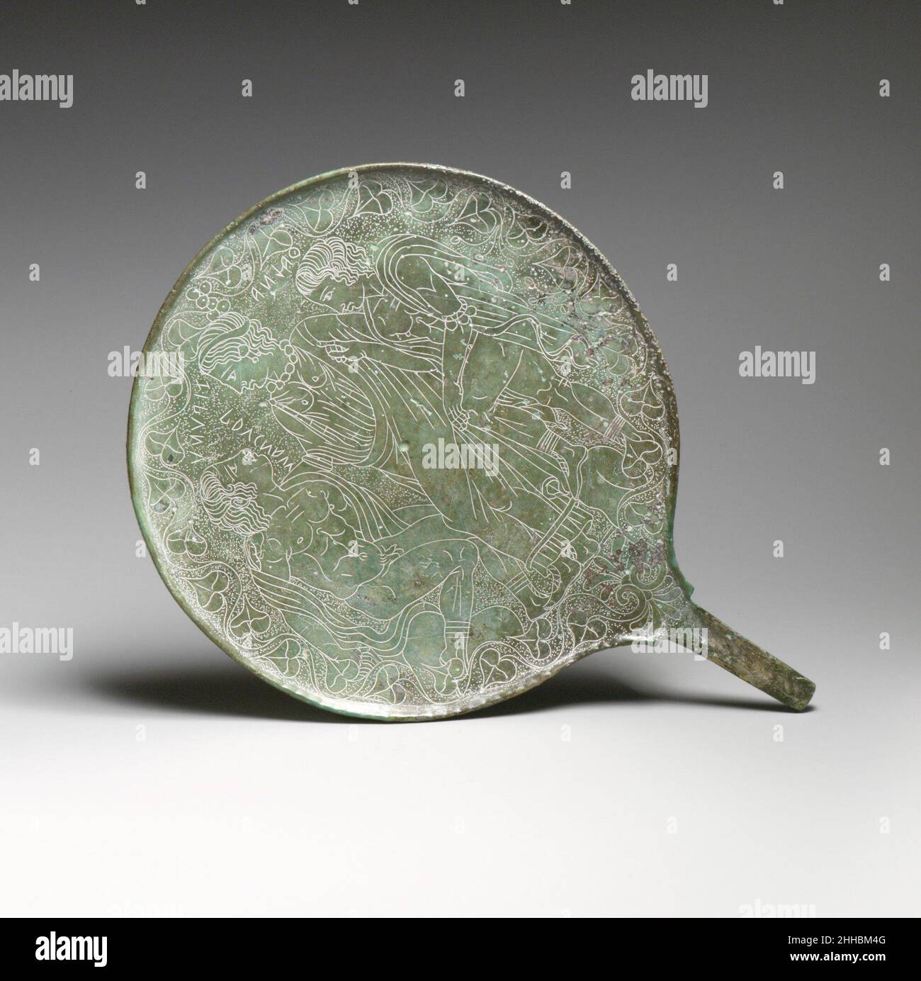 Specchio in bronzo ca. 350–300 a.C. Zipunu etrusco fiancheggiato da Prucnas e iscrizioni ThalnaEtrusche identificano i caratteri piuttosto oscuri qui raffigurati. Al centro si trova Zipunu, una piccola dea etrusca spesso associata al Turano (latino: Venere). È affiancata dagli oscuri eroi etruschi Prucnas e Thalna. L'incisore prestò meticolosa attenzione ai dettagli degli occhi, dei capelli, delle unghie, delle calzature, dei gioielli, e muscolatura. Le cifre sono riportate su un insolito sfondo soffocato. Specchio in bronzo 251234 Etrusco, specchio in bronzo, ca. 350?300 a.C., Bronzo, 9 1/4 x 6 11/16in. (23,5 x 17cm Foto Stock