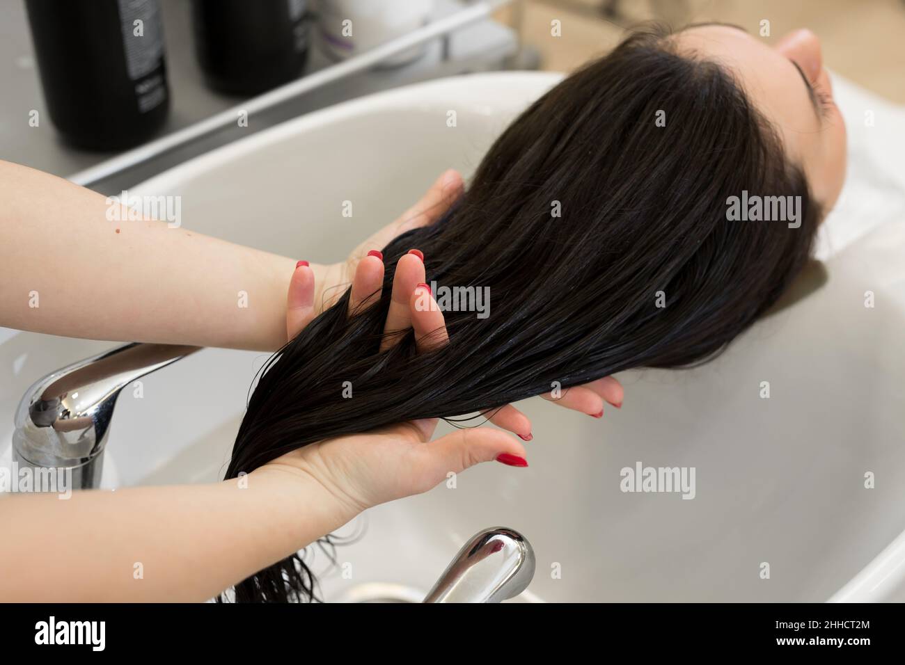 Primo piano della mano di un parrucchiere che sfrega l'olio idratante nei  capelli del cliente. Parrucchiere applica una maschera terapeutica sui  capelli della ragazza Foto stock - Alamy