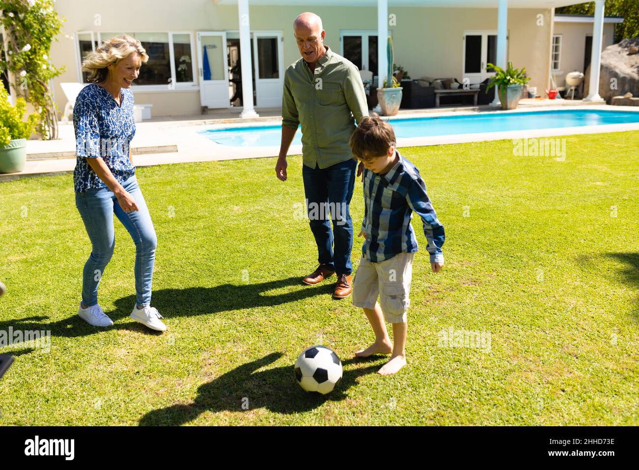 Nonni caucasici e nipote che giocano a calcio insieme in giardino Foto Stock