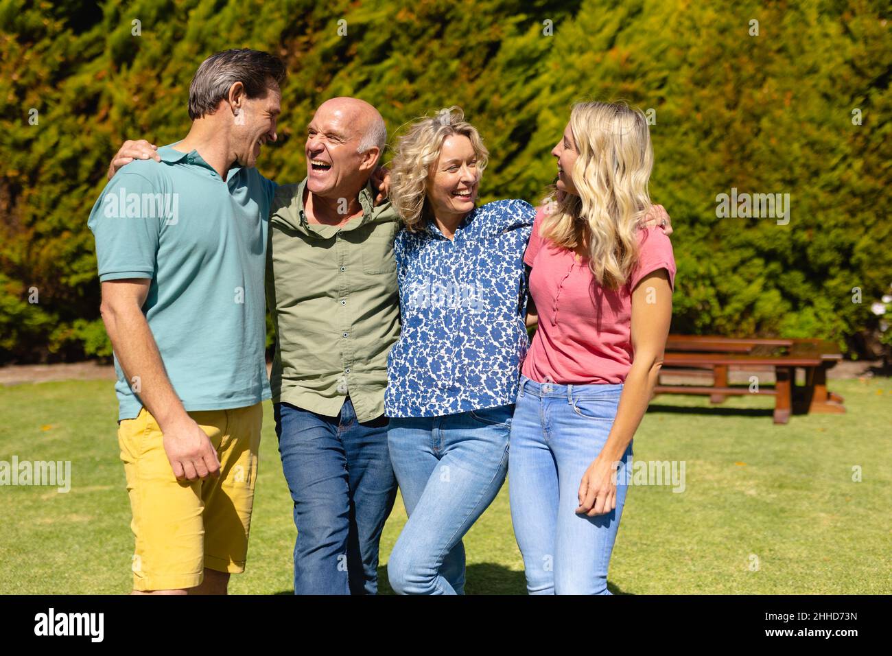 Famiglia caucasica di due generazioni sorridendo guardando l'un l'altro mentre si levano in piedi insieme nel giardino Foto Stock