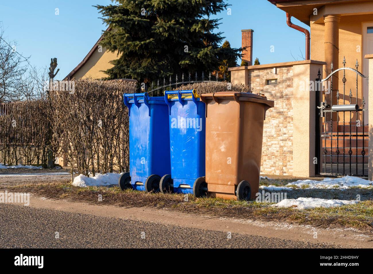 Tre contenitori di plastica per il riciclaggio dei rifiuti di fronte ad una piccola casa in un villaggio Foto Stock