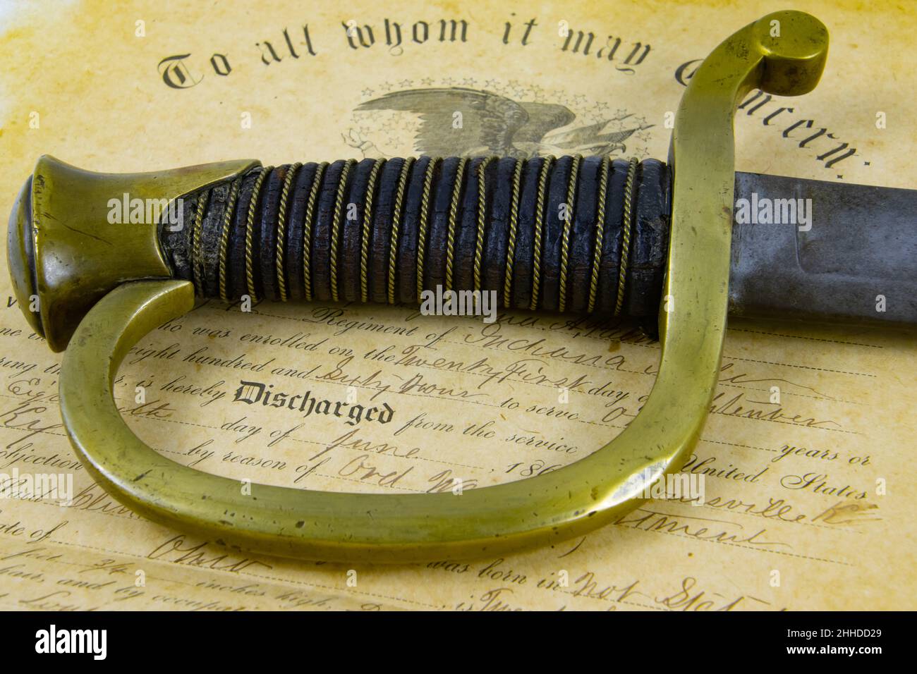 Vecchio Sabre che giace su un documento storico di certificato di scarico dell'esercito dell'Unione dal 1863 con fuoco sulla maniglia Foto Stock