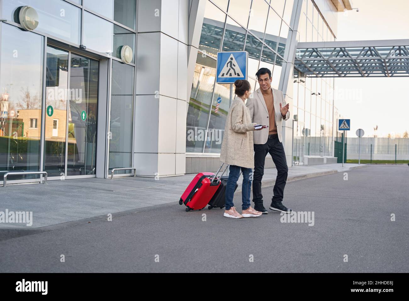 Donna con biglietti che parlano con uomo fuori dall'aeroporto Foto Stock