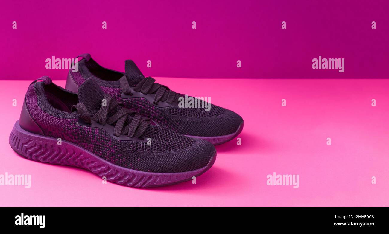 Design sneakers con spazio per il testo. Primo piano di sneaker rosa su sfondo luminoso. Scarpe sportive per la corsa e il fitness. Paio di scarpe. Stile di vita attivo. Texture con suola viola e lacci. Foto Stock