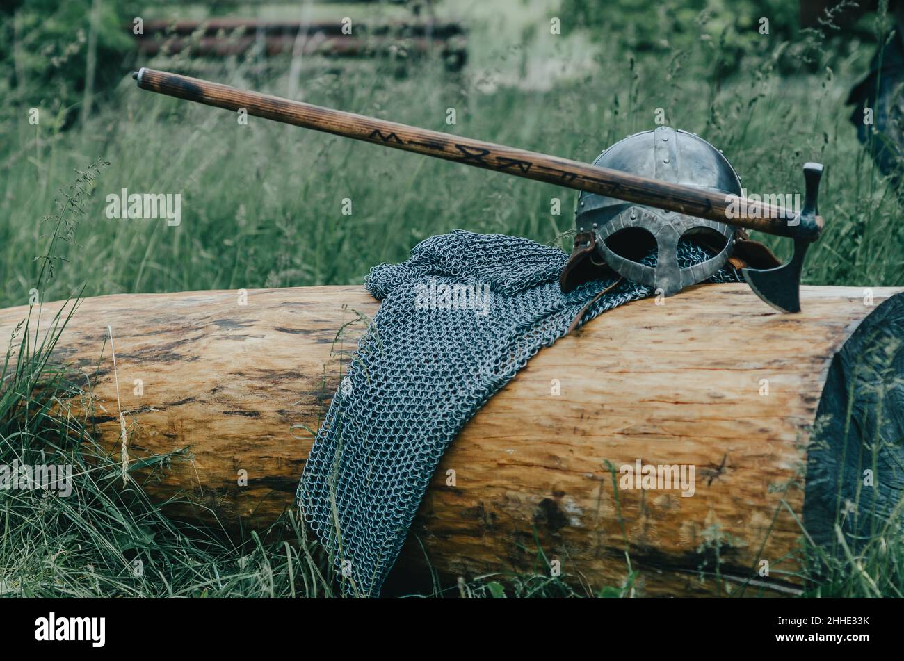 Catena metallica posta, casco e ascia giacciono su tronchi di legno. Armatura vichinga. Concetto di film storico. Foto Stock