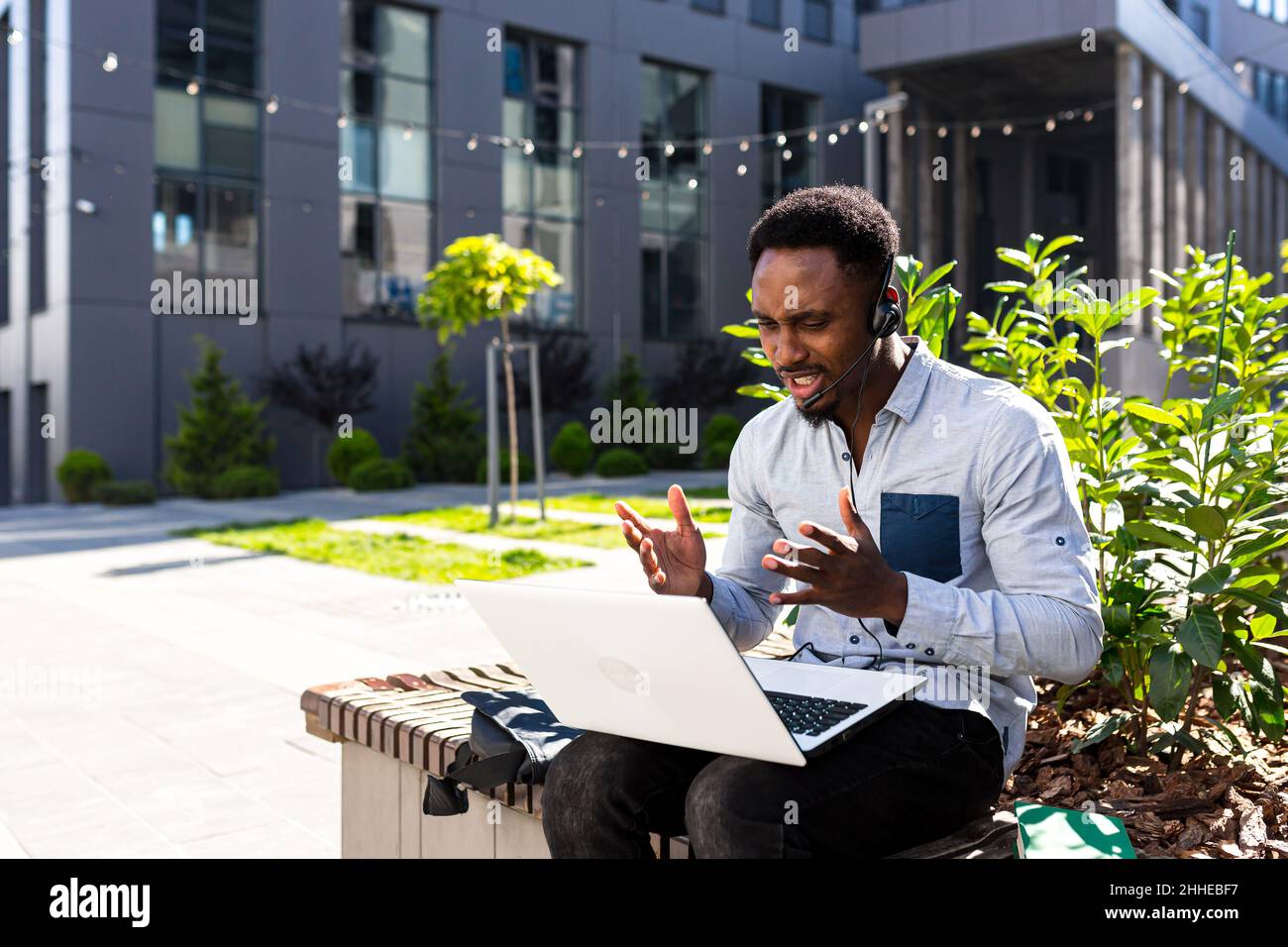 Arrabbiato, irato africano americano maschio freelancer lavoro litigare in remoto online con cuffie e laptop. Videochiamata conferenza o distanze meetin Foto Stock