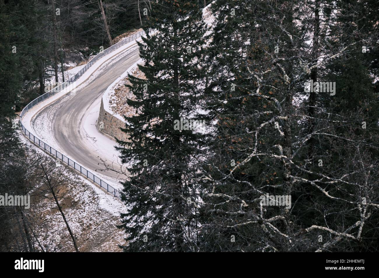 Strada invernale, neve su strada e strada ghiacciata dietro la pineta, curva. Foto Stock