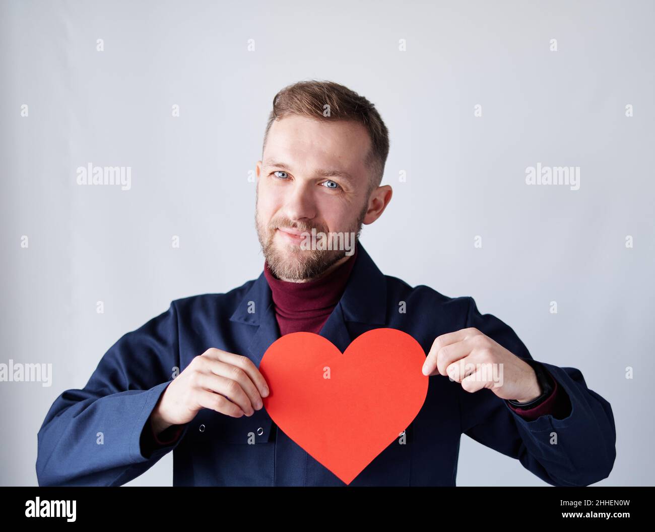 San Valentino o tema d'amore: Uomo tecnico, appaltatore, supervisore o ingegnere indossando uniforme blu tenendo rosso carta forma cuore. Romanticismo o concetto di relazioni. Immagine di alta qualità Foto Stock