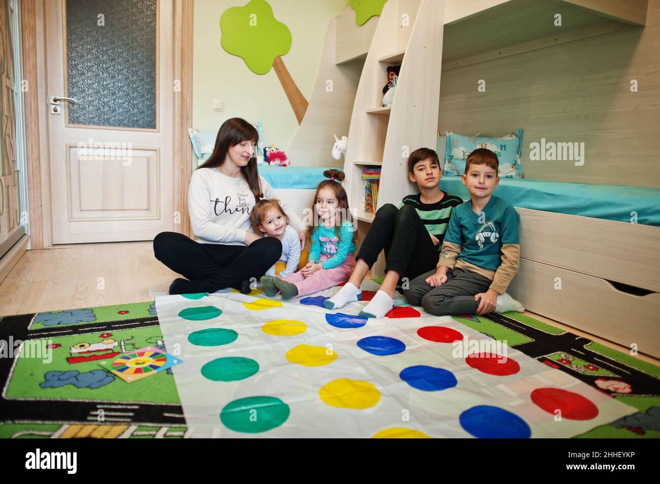 Famiglia felice divertirsi insieme, quattro bambini e la madre giocare twister  gioco a casa Foto stock - Alamy