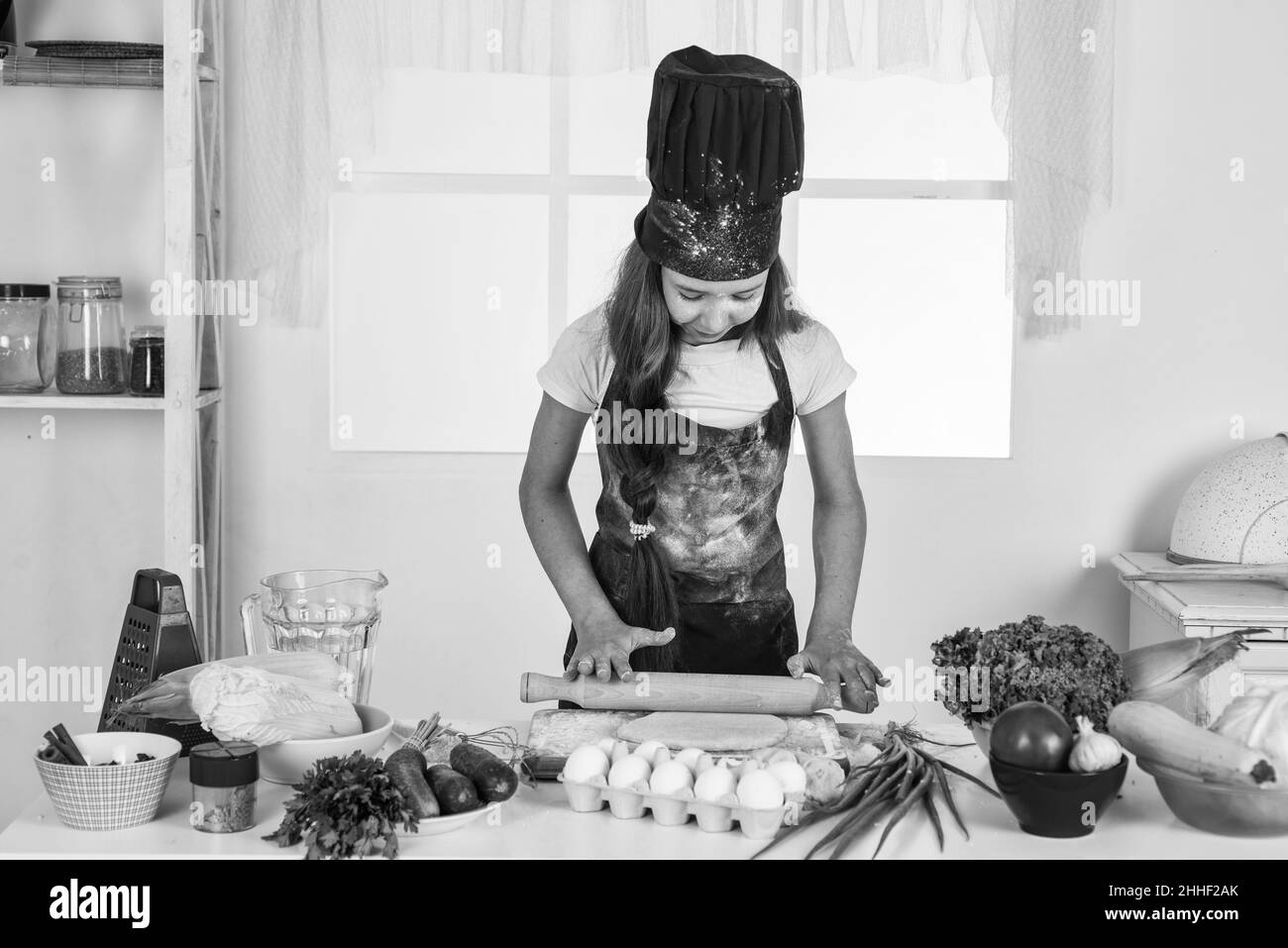 l'adolescente mangia sano. indossa uniforme di cuoco. pulizia e aiuto domestico. sviluppo d'infanzia. cottura della bambina in cucina. cucina del cuoco del capretto Foto Stock