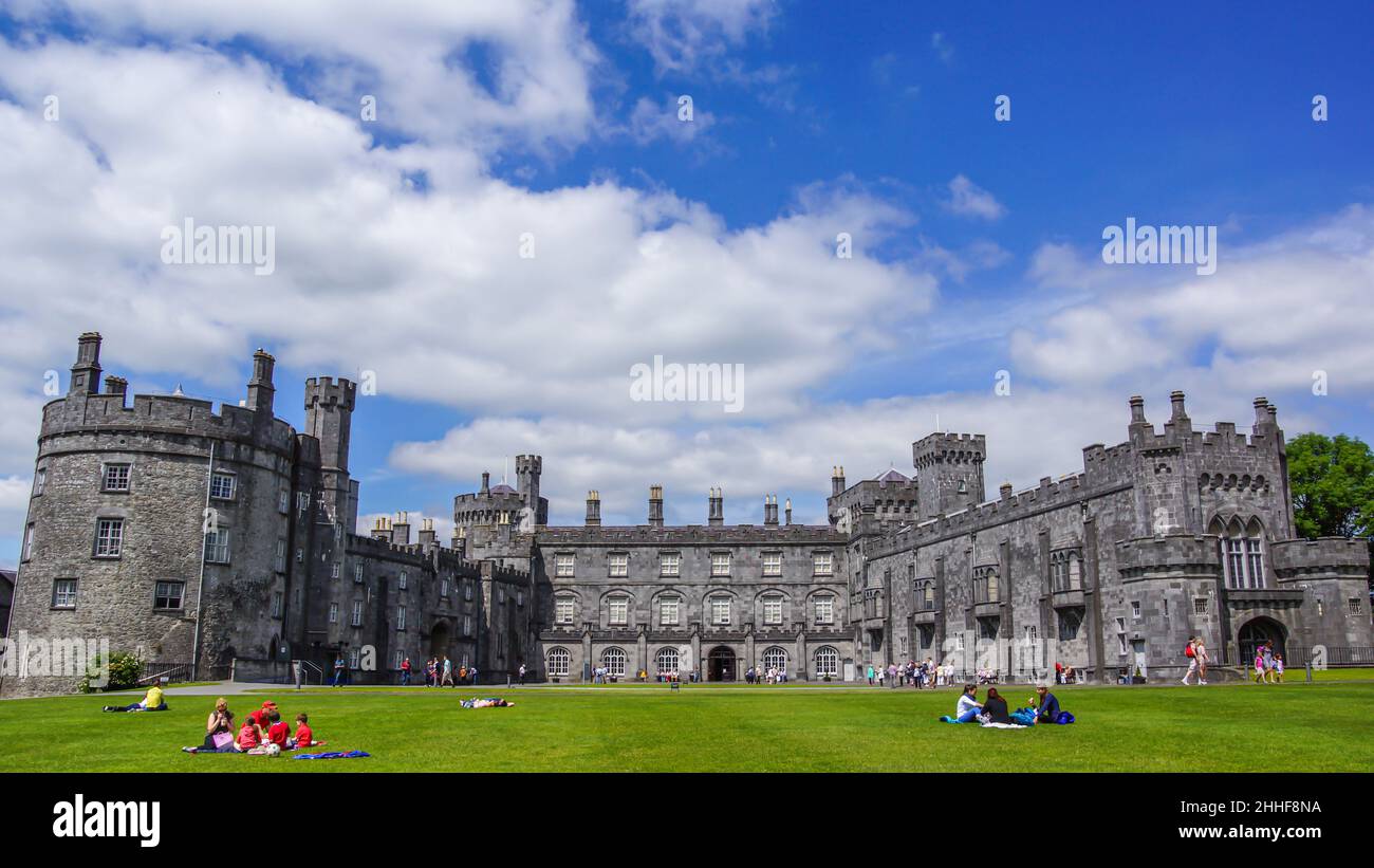 Kilkenny Castle im Sommer mit Touristen im Vordergrund die auf dem Rasen sitzen Foto Stock