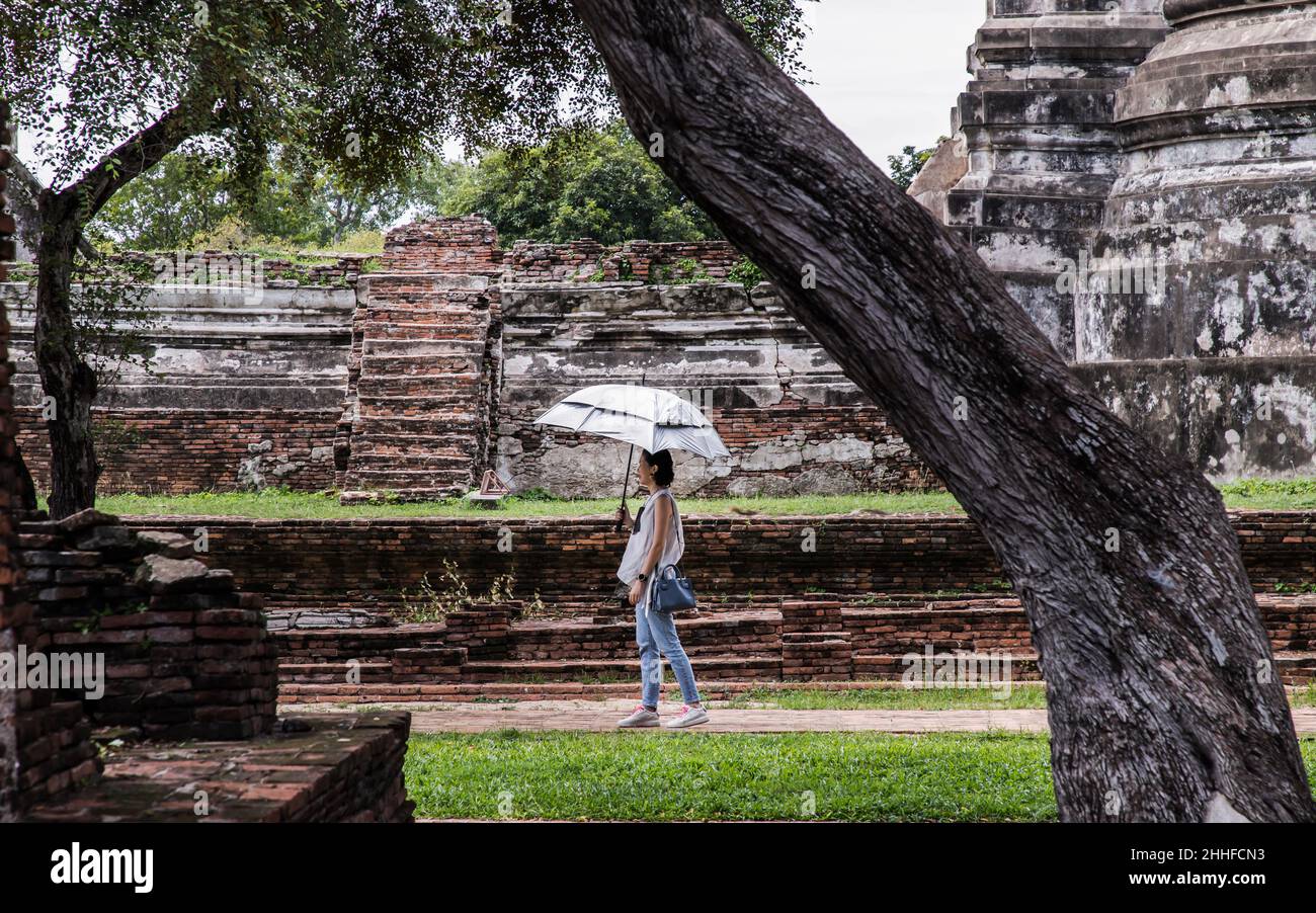 Aytthaya, Thailandia, 22 ago 2020 : donna turistica che tiene un ombrello d'argento e cammina a Wat Ratchaburana. Provincia di Ayutthaya, non focus, in particolare. Foto Stock