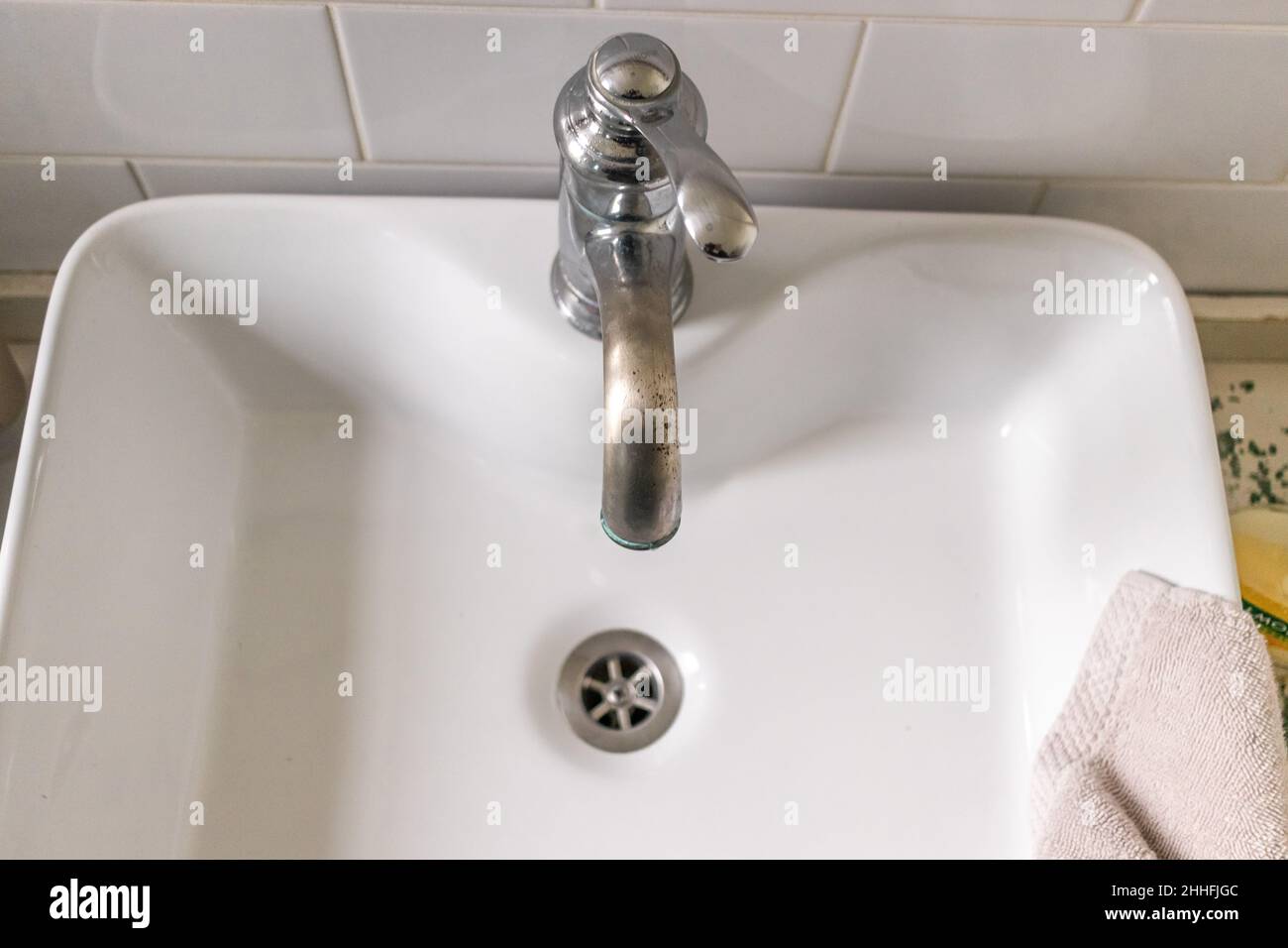 Lavello bianco su banco di legno con uno specchio appeso sopra di esso. Bagno interno. Foto Stock
