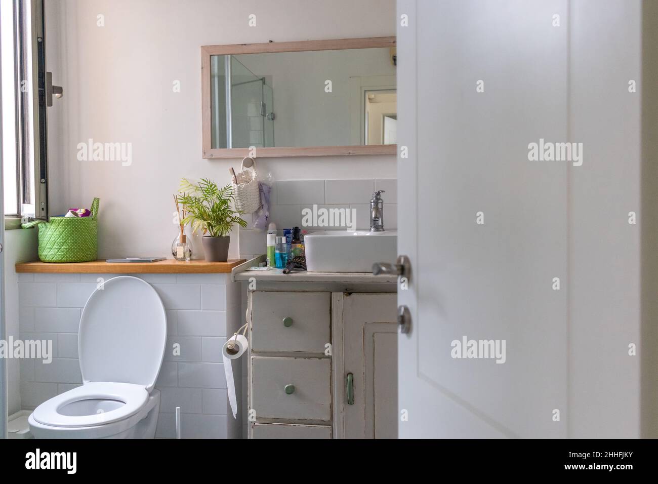 Lavello bianco su banco di legno con uno specchio appeso sopra di esso. Bagno interno. Foto Stock