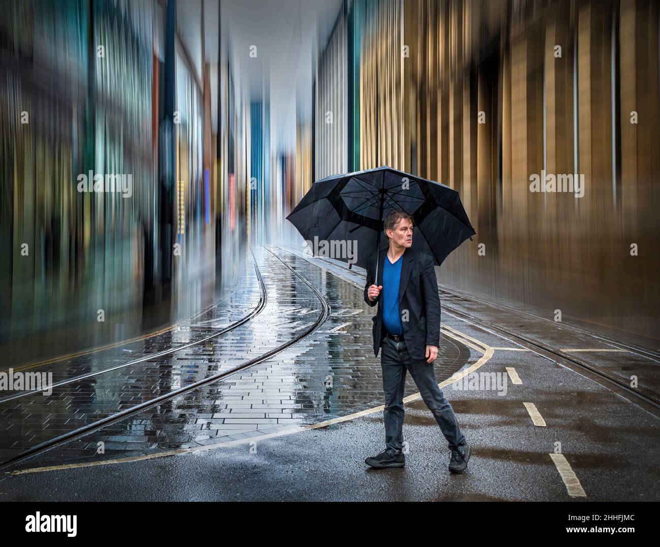 Uomo con ombrello nella città piovosa Foto Stock
