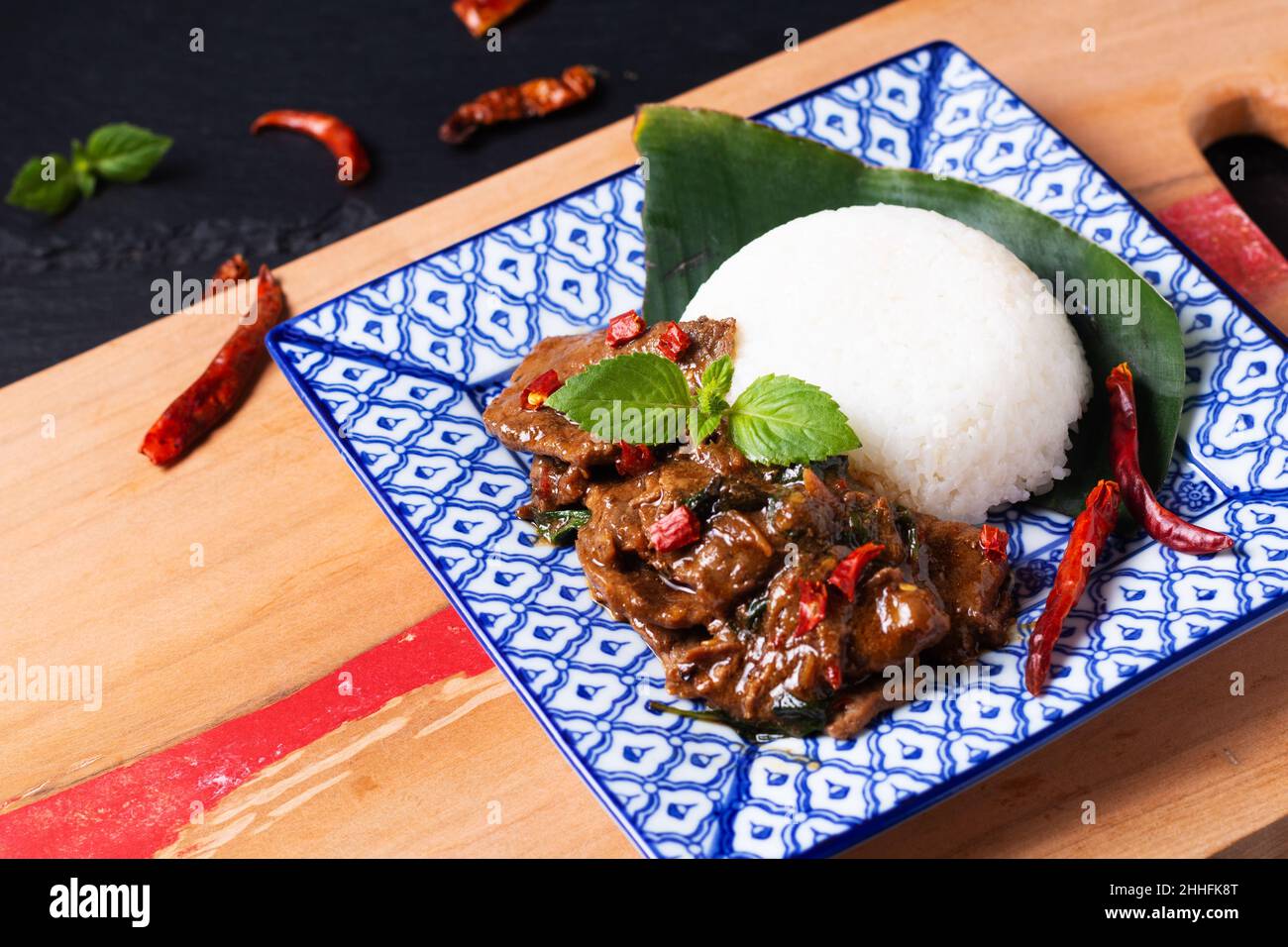 Asian Food Concept Thai Santo Basilio Beef Stir Fry e Jasmine Rice Khao Pad Pad Kra Pow Nua nella tradizione tailandese piastra in ceramica su tavola di legno e nero s. Foto Stock