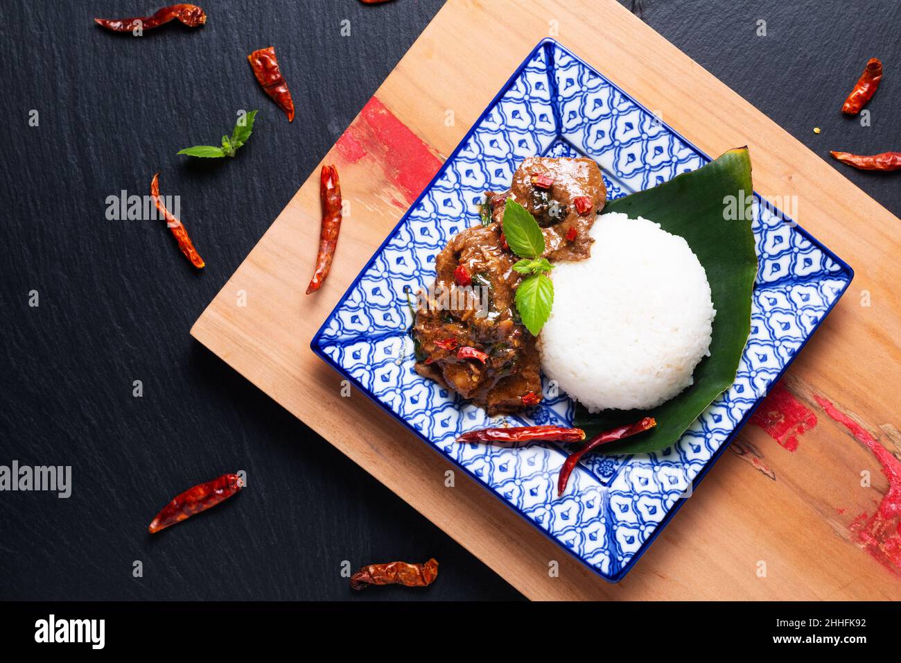 Asian Food Concept Thai Santo Basilio Beef Stir Fry e Jasmine Rice Khao Pad Pad Kra Pow Nua nella tradizione tailandese piastra in ceramica su tavola di legno e nero s. Foto Stock