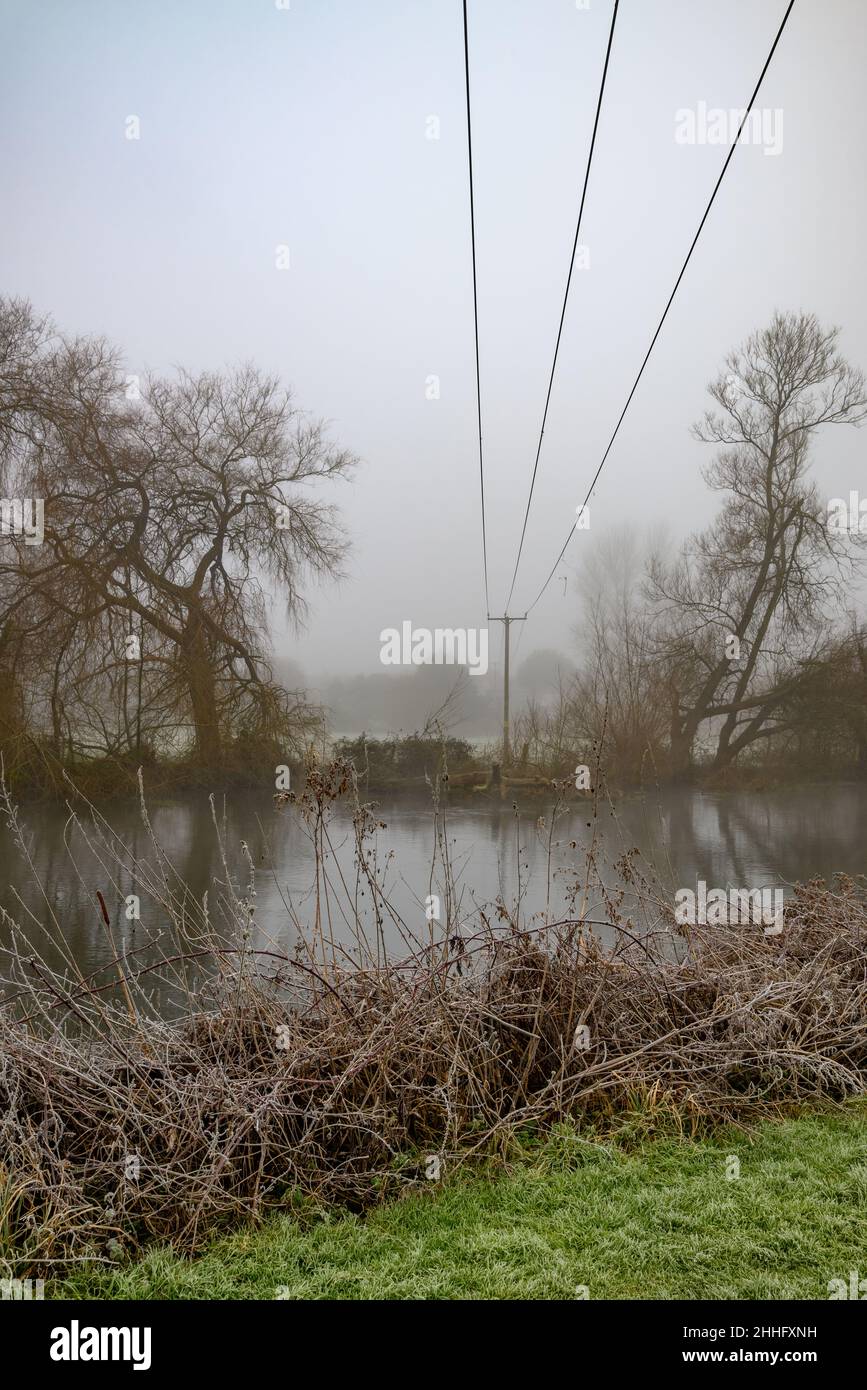 Linee elettriche che attraversano, attraversano, un fiume, Regno Unito in inverno Foto Stock