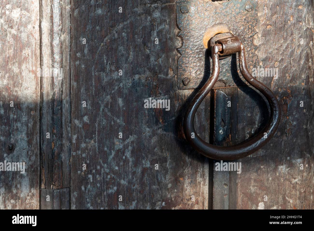 Maniglia per porta in metallo per impieghi pesanti su una vecchia porta in legno Foto Stock