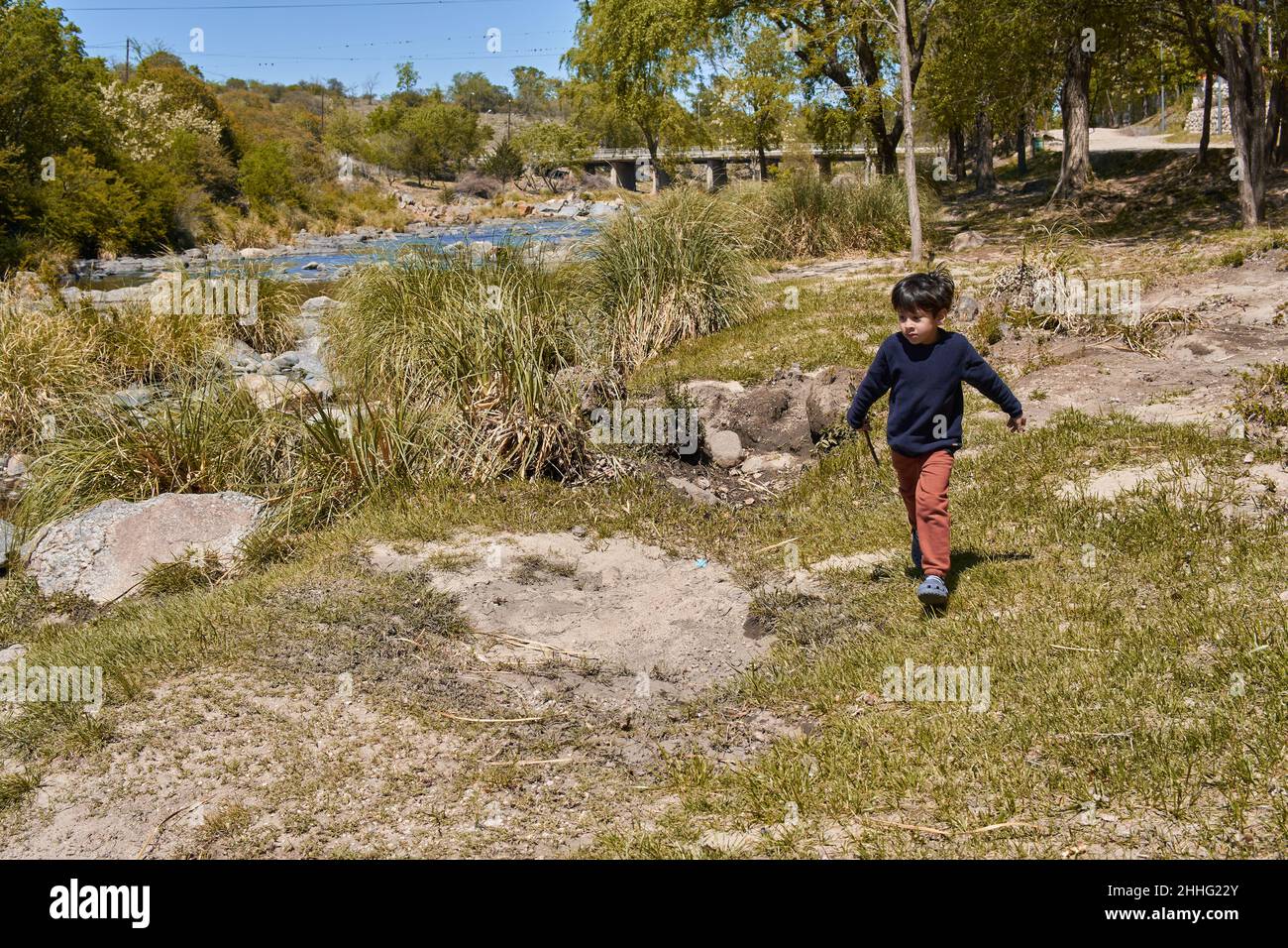 ragazzo latino che cammina da solo lungo la riva di un torrente a cordoba argentina in autunno in vacanza. Orizzonte Foto Stock
