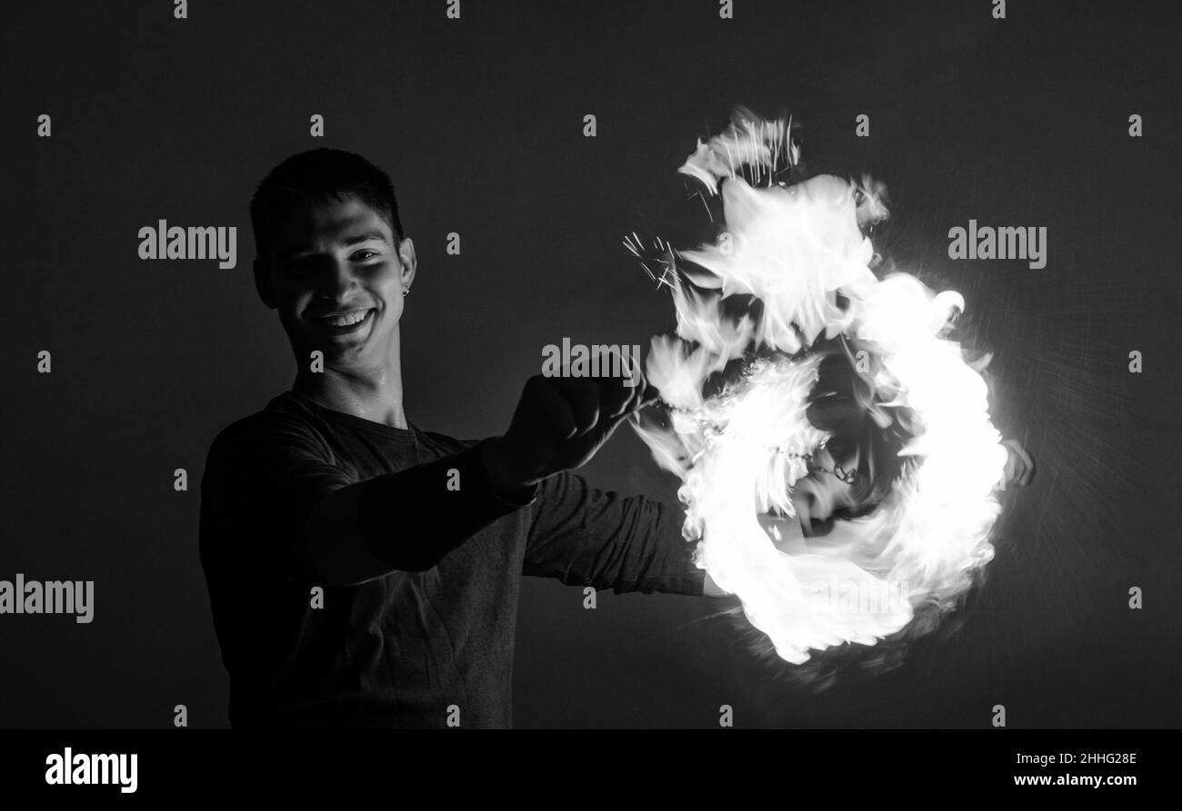 Happy Guy artista eseguire cerchio di fuoco ruotando poi bruciante su idilliaco cielo scuro di notte all'aperto, orbitale Foto Stock