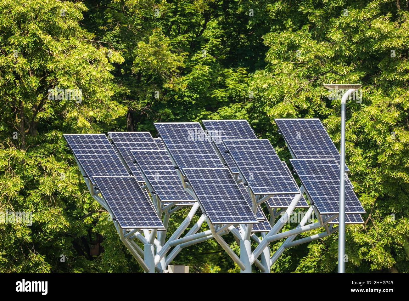 Pannelli solari contro il verde fogliame, moduli fotovoltaici, fonti di energia rinnovabile sostenibile. Foto Stock