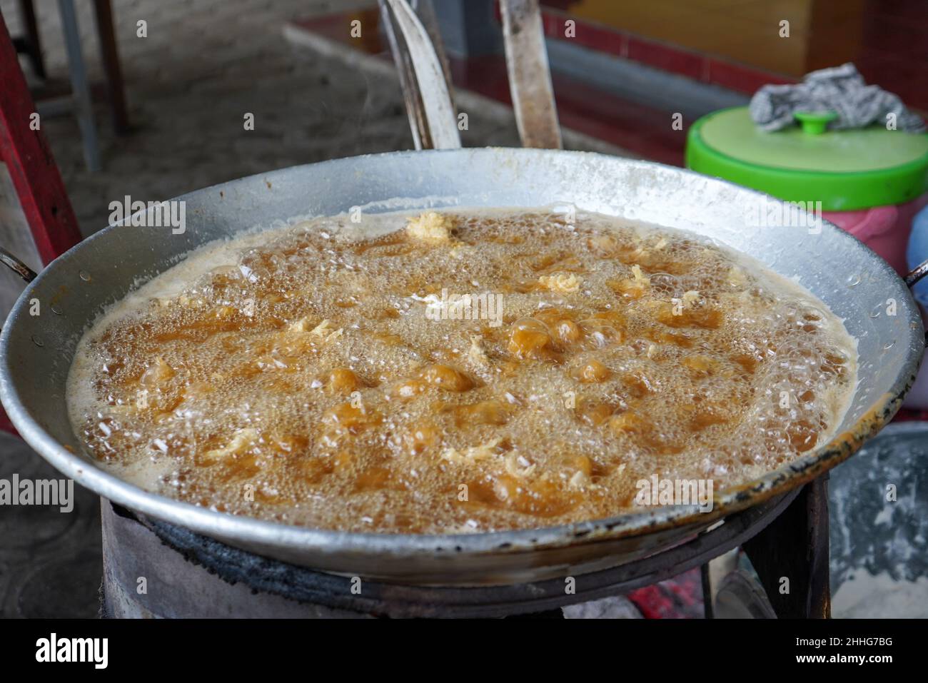 Friggere il pollo infarinato in olio caldo in una padella grande. Foto Stock