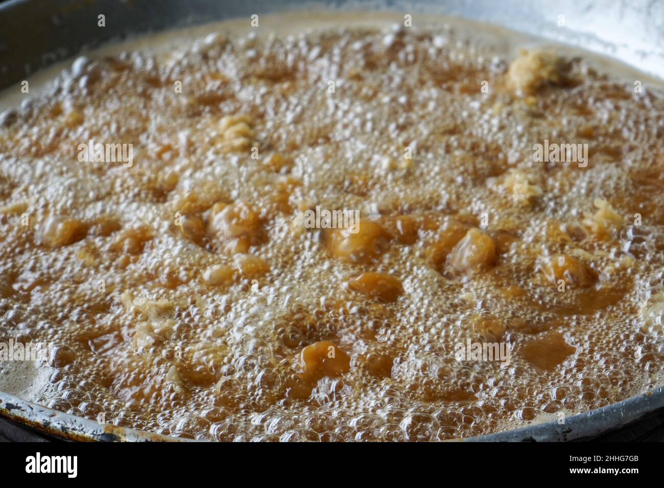 Friggere il pollo infarinato in olio caldo in una padella grande. Foto Stock