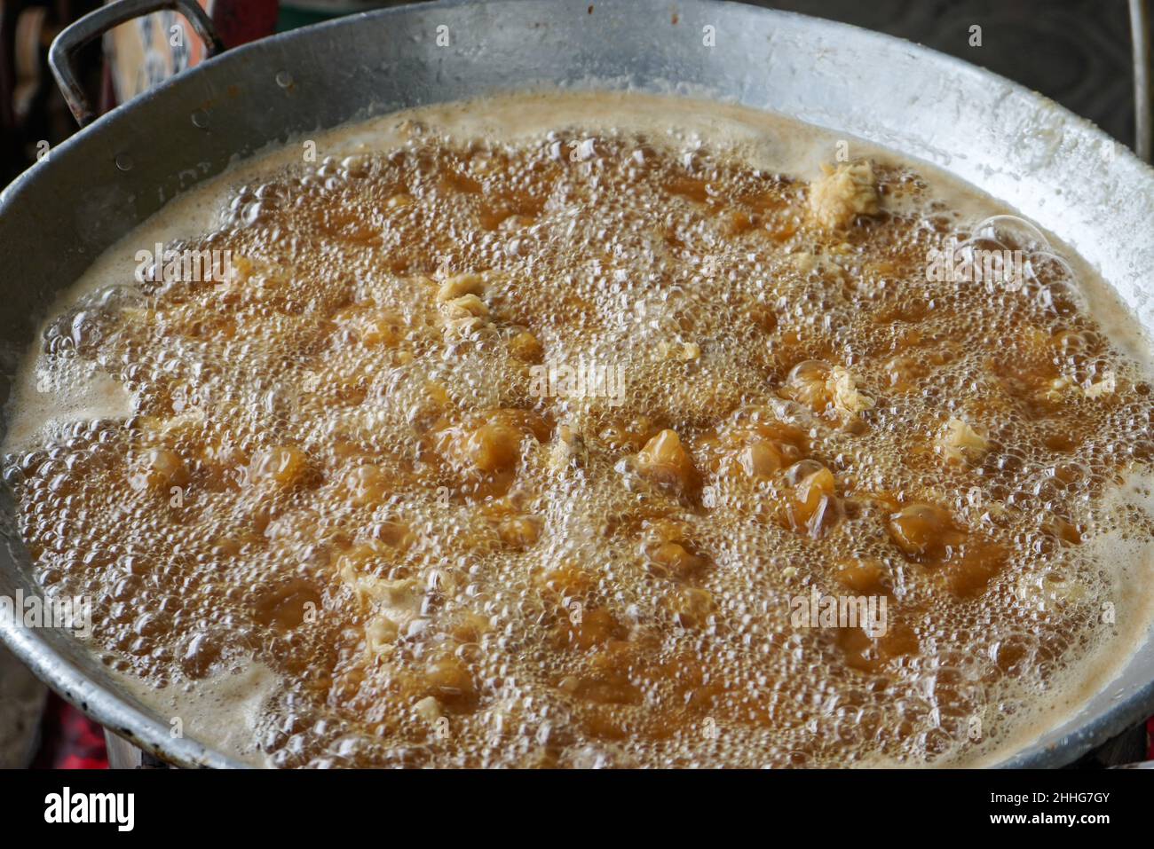 Friggere il pollo infarinato in olio caldo in una padella grande. Foto Stock