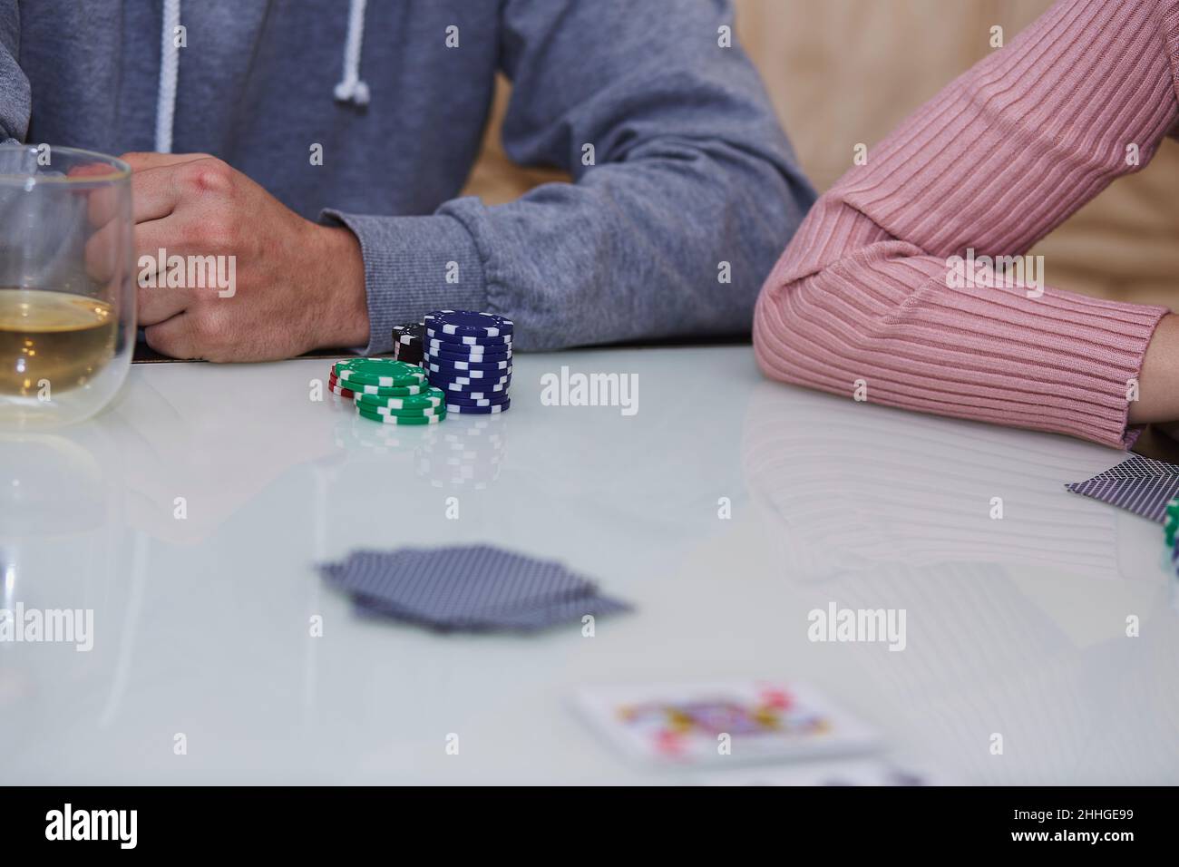 L'uomo e la donna mani in un gioco di poker. Chip, carte, bicchiere di whiskey sul tavolo con riflessione. Fotografia di stile di vita. Poker club. Foto Stock