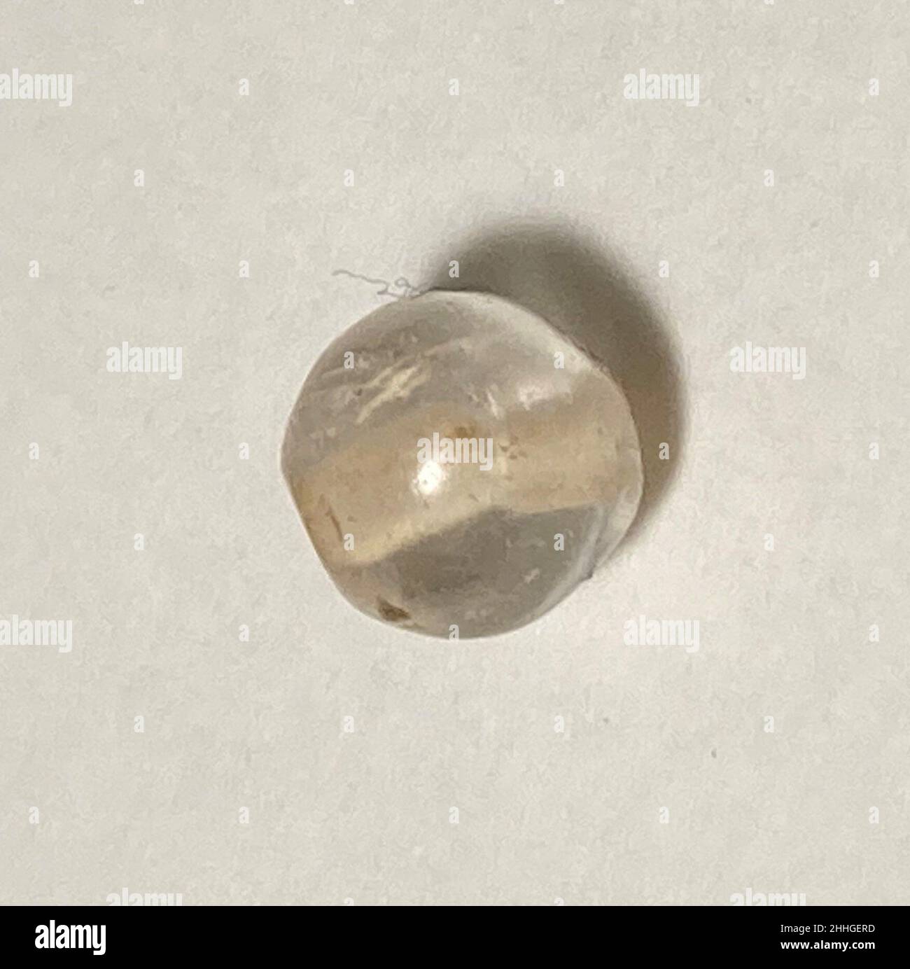 Bead 8th–13th secolo questo oggetto è stato scavato a Nishapur.Nishapur era una città vitale nel periodo islamico iniziale e medio, situata lungo una delle traiettorie principali che collegavano l'Iran e le terre islamiche dell'Asia occidentale con l'Asia centrale e la Cina. Questi itinerari sono spesso indicati con il termine ‘percorsi Silk’, ma sono stati di fatto cruciali per il movimento di costellazioni di materiali e oggetti, nonché di persone e idee. La variegata popolazione di Nishapur e dei suoi dintorni, dai gruppi d'élite meglio ricercati di mercanti, aristocrazia proprietaria e letterati, ai meno conosciuti arti Foto Stock