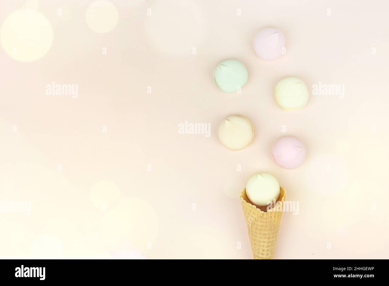 Il corno di waffle con marshmallow colorato assomiglia a macaroon su uno sfondo rosa pastello. Vista dall'alto. Spazio libero per il testo Foto Stock